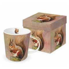 A ceramic mug and matching gift box featuring a red squirrel holding a nut, set against a soft pink and brown background with small gold speckles.