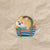 An embroidered patch featuring a light brown dog peeking out from a green, blue, red, and white striped basket,.
