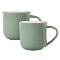 Two porcelain mugs in a soft sage green color with white interiors.